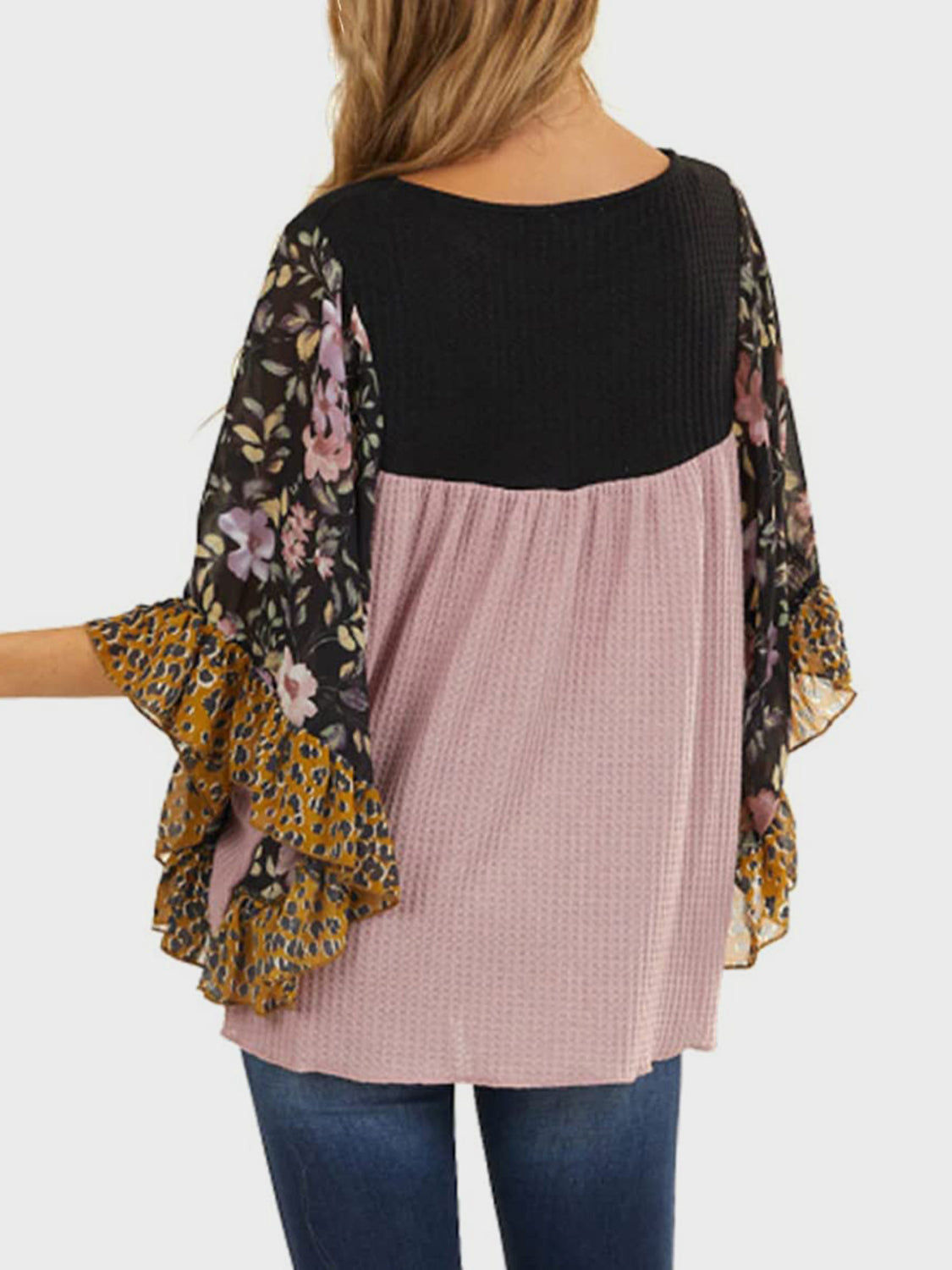 Blouse with black waffle knit, pink waffle knit body, and floral print flutter sleeves.