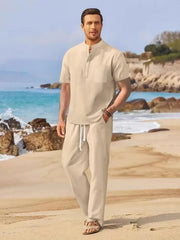 Beige linen henley shirt and drawstring trousers set on a beach