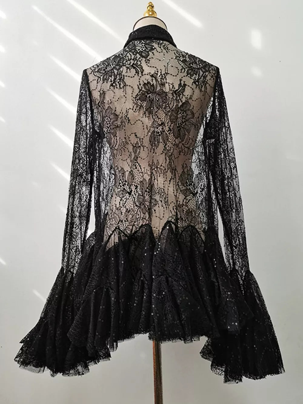 Black floral lace dress with long sleeves, ruffle hem, and sequin details.