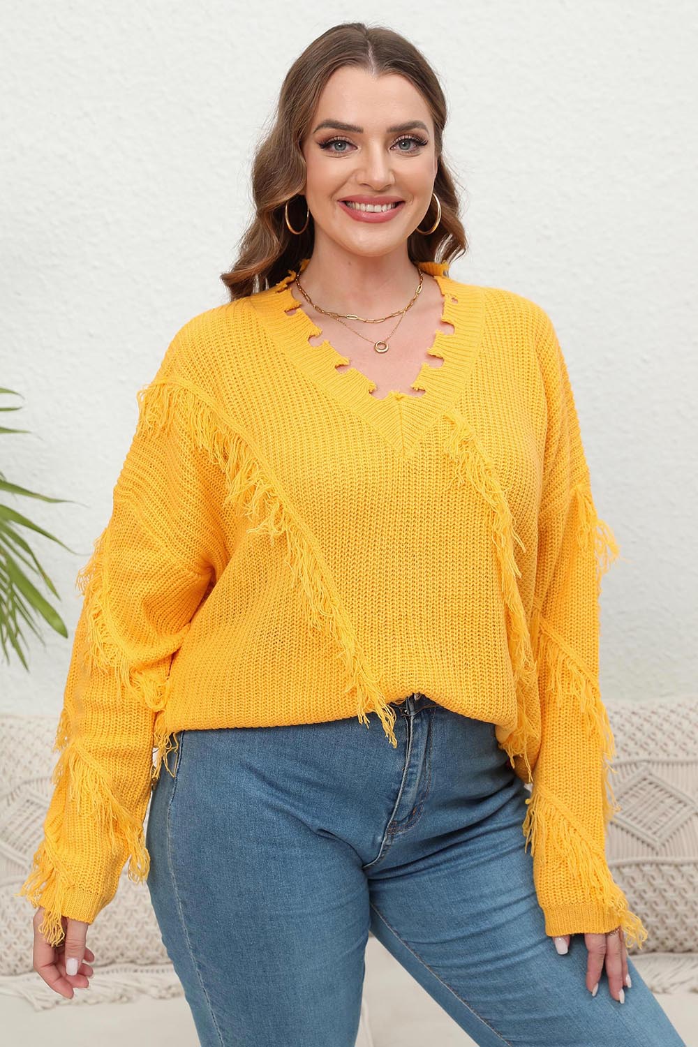 Banana yellow knit sweater with v-neck and fringe trim.