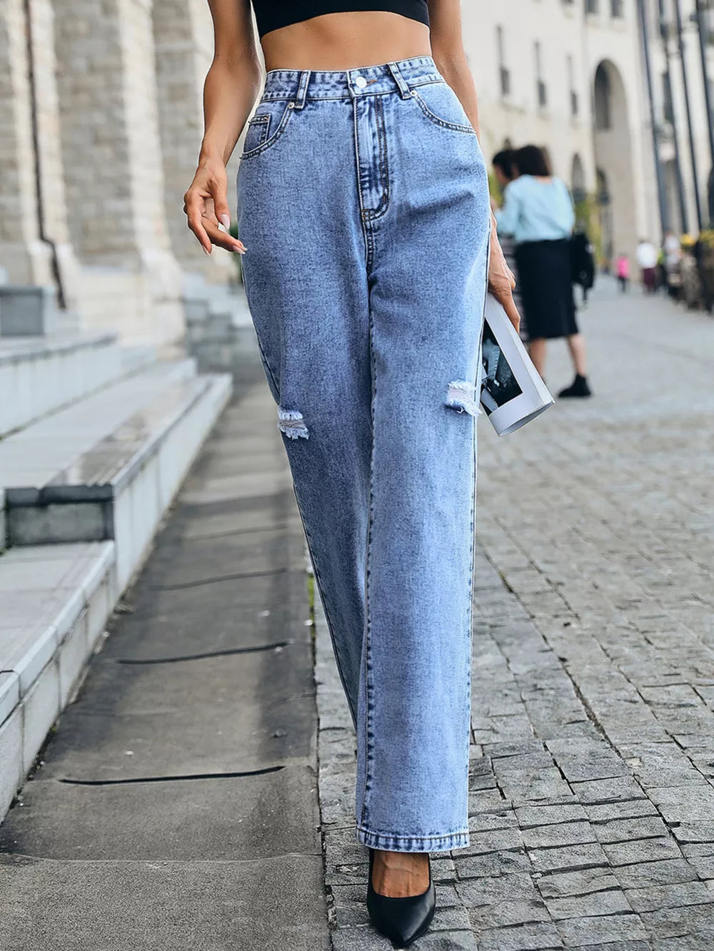 Ripped high-waisted denim jeans in light blue with button closure and a relaxed fit.