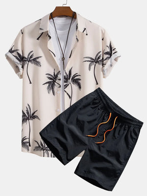Men's tropical print short sleeve button-down shirt in pale blush with black palm trees and black drawstring shorts.