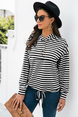 Black and white striped hoodie with button neck and drawstring waist detail.