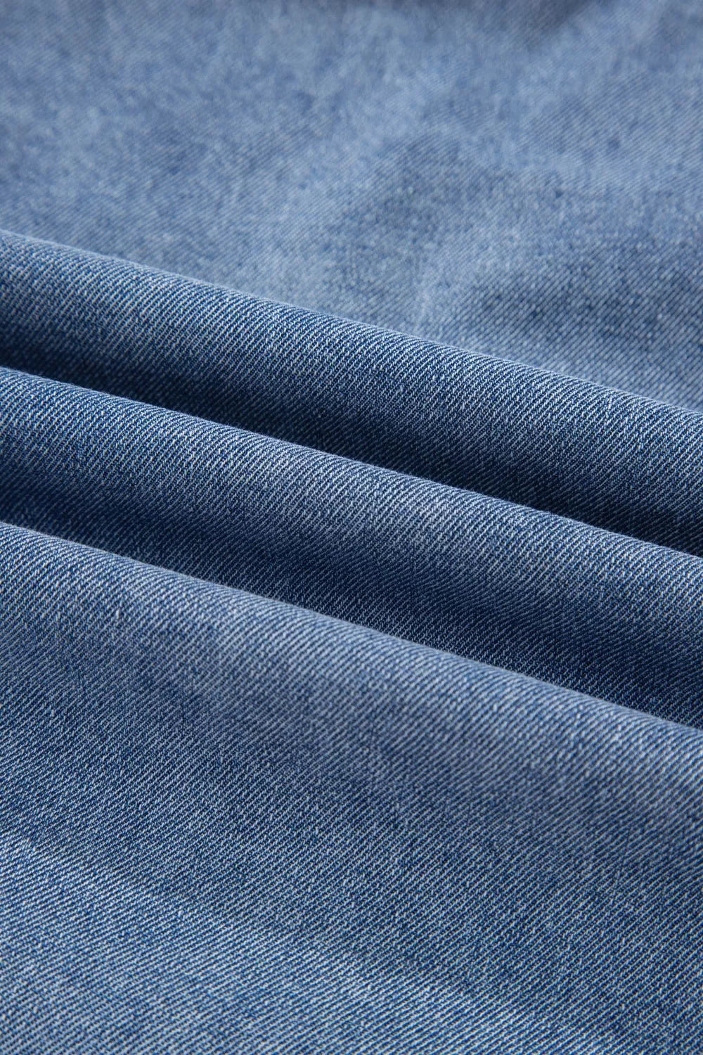 V-shaped pleated denim sleeveless top in blue denim with a textured weave.