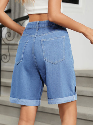 Medium wash denim bermuda shorts with cuffed hems and a heart appliqué detail.