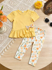 Light yellow ruffle top with floral bow and matching floral print leggings.