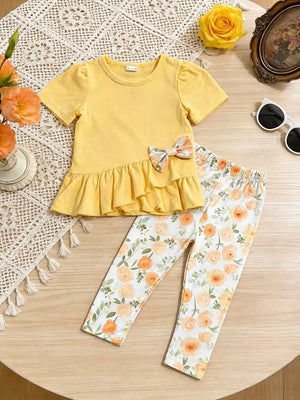 Light yellow ruffle top with floral bow and matching floral print leggings.