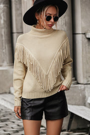 Beige knit turtleneck sweater with chevron fringe detail and long sleeves.