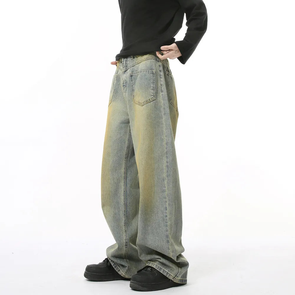 Distressed denim jeans in a medium wash with yellowing accents, wide leg, and relaxed fit.