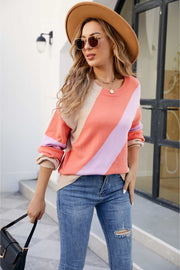 Diagonal colorblock knit sweater in orange, coral, and lavender with a crew neck.