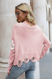 Blush pink acrylic sweater with daisy appliqué and distressed hem.