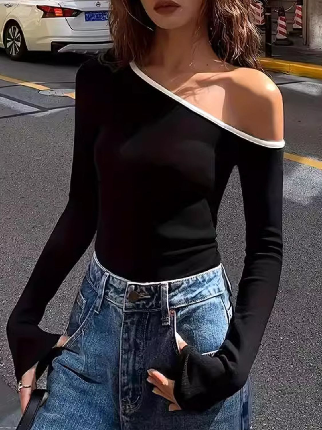 Black ribbed off-shoulder top with contrast trim and long sleeves.