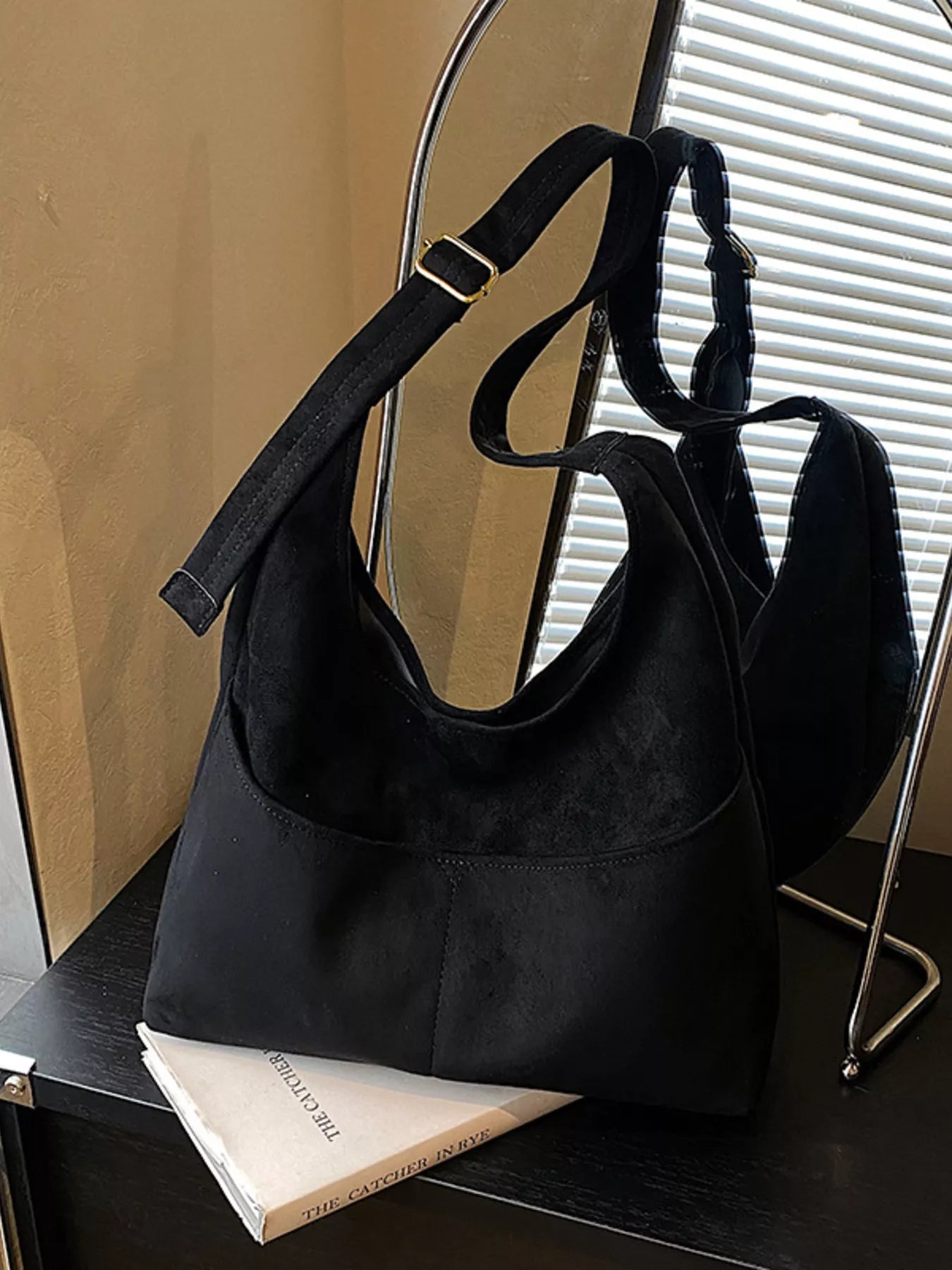 Black suede and fabric shoulder bag with adjustable strap and gold buckle detail.