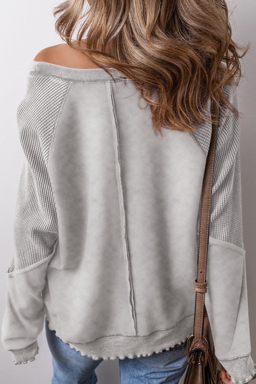 Gray waffle knit raglan sweatshirt with contrast panels and raw hem detail.