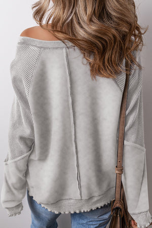 Gray waffle knit raglan sweatshirt with contrast panels and raw hem detail.