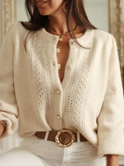Cream knit button-up cardigan with open panel details and pearl buttons.