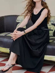 Black fitted midi dress with a flowing skirt and scoop neck.