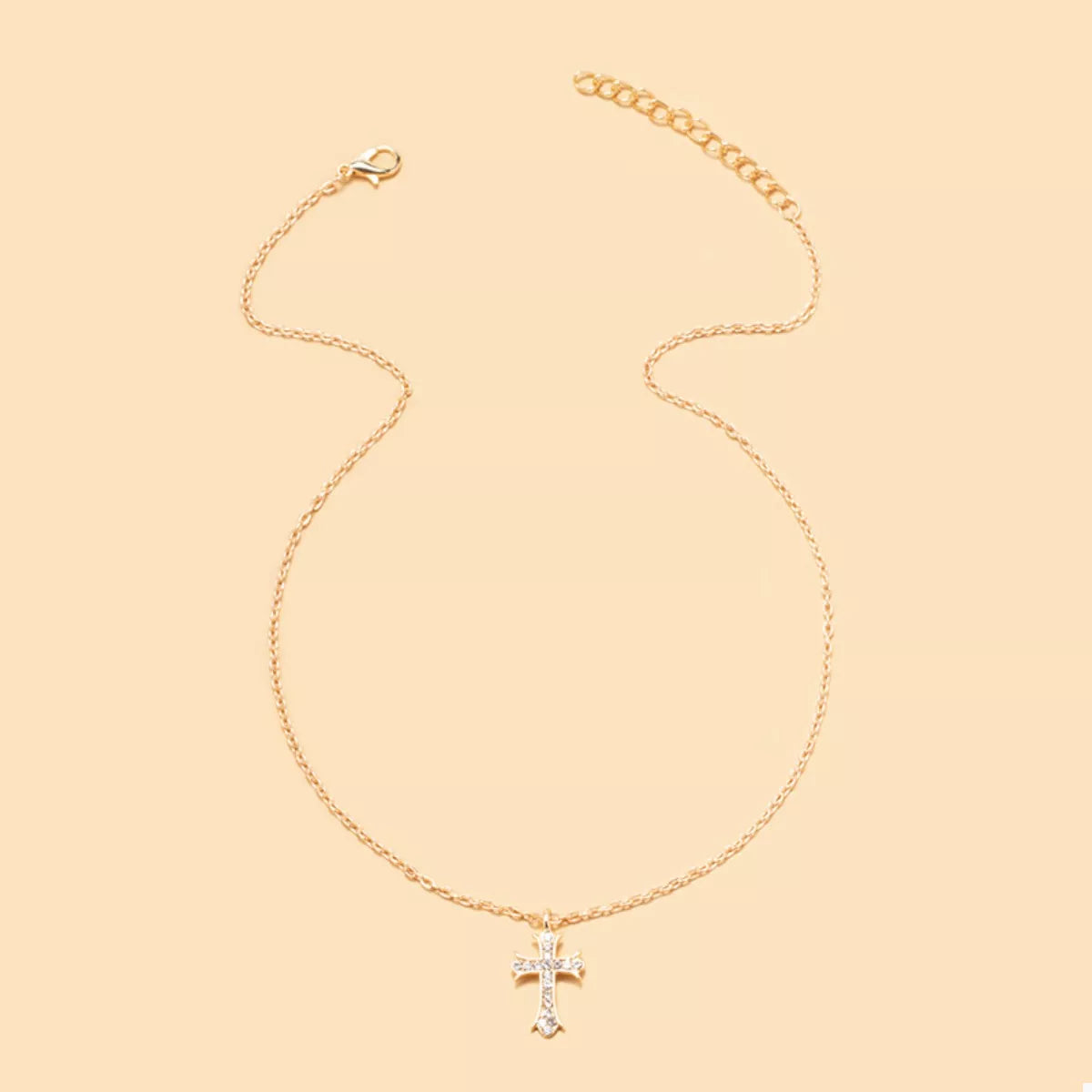 Gold rhinestone cross pendant necklace with a delicate chain.