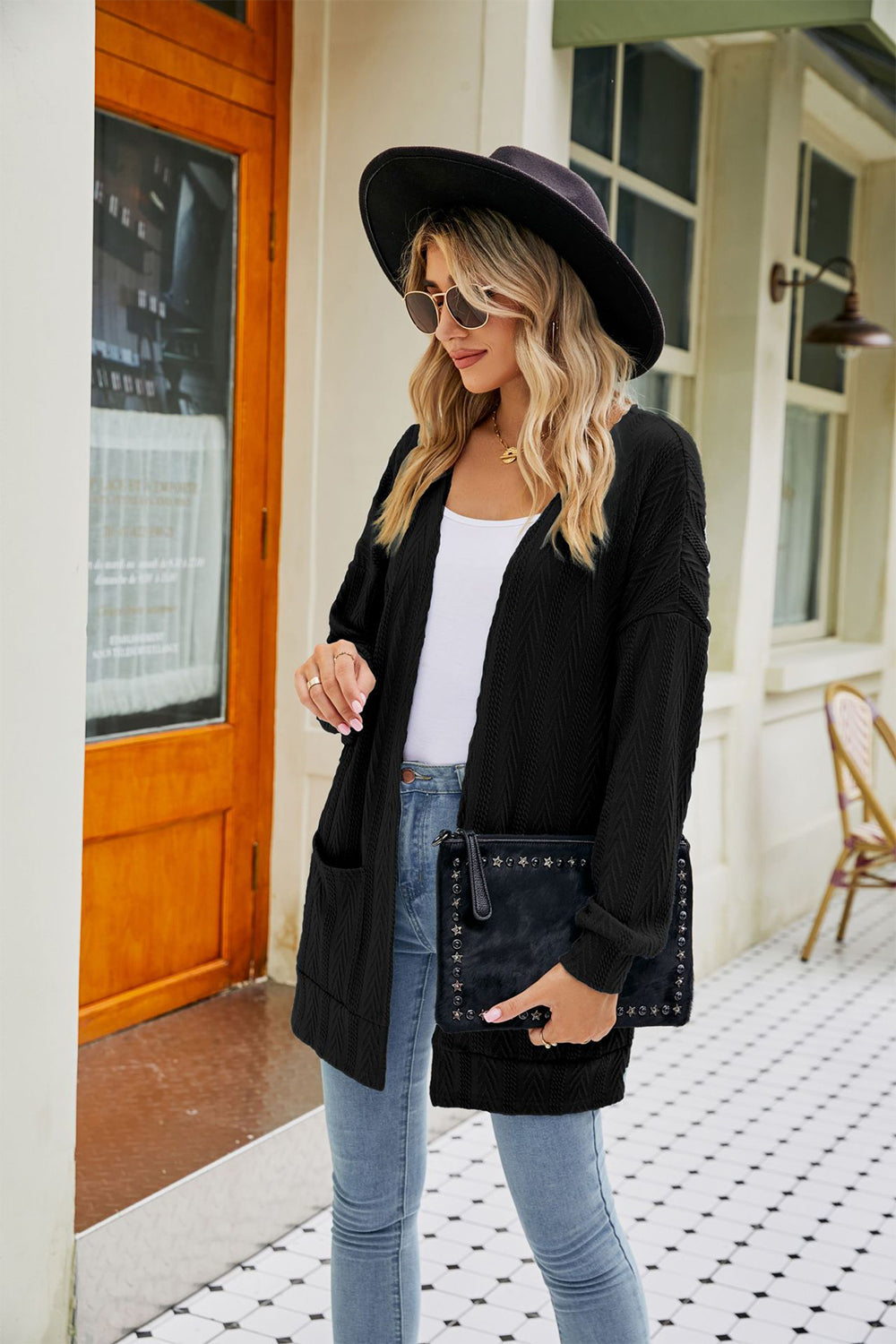 Black cable-knit cardigan with pockets and chevron pattern sleeves.