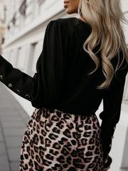 Black blouson sleeve top with button cuffs paired with leopard print skirt