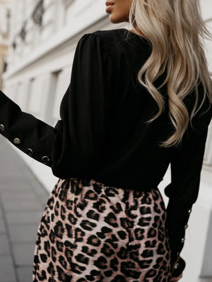 Black blouson sleeve top with button cuffs paired with leopard print skirt