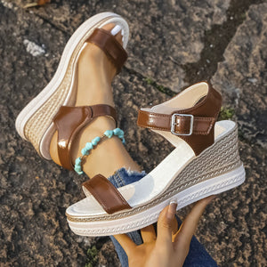 Brown open-toe wedge sandals with adjustable ankle strap and espadrille wedge detail.