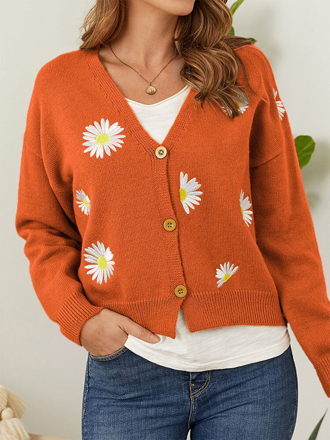 Orange V-neck cardigan with allover white daisy embroidery and button front.