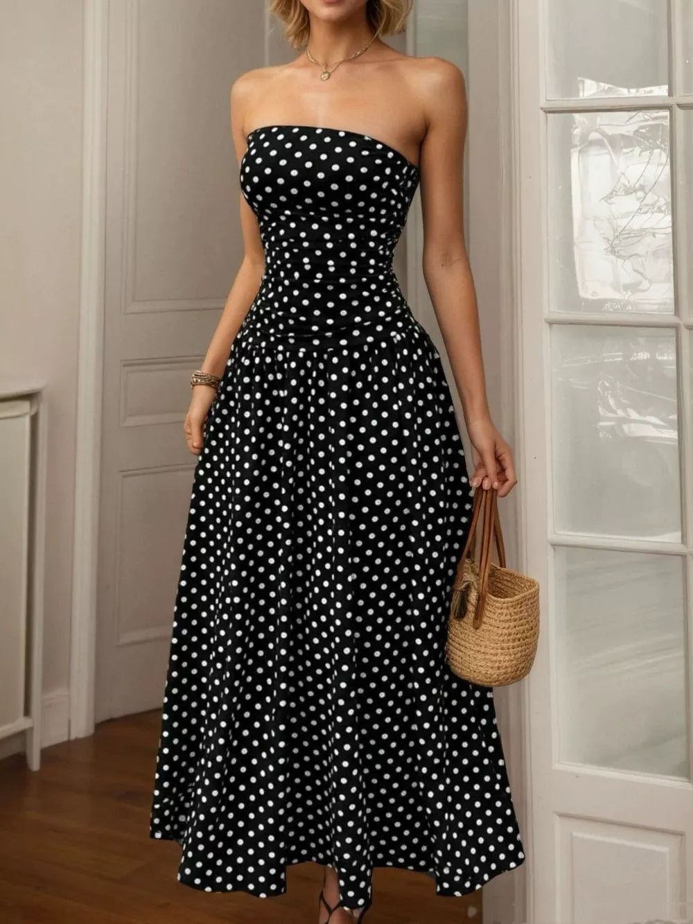 Black polka dot strapless maxi dress with a ruched bodice and full skirt.