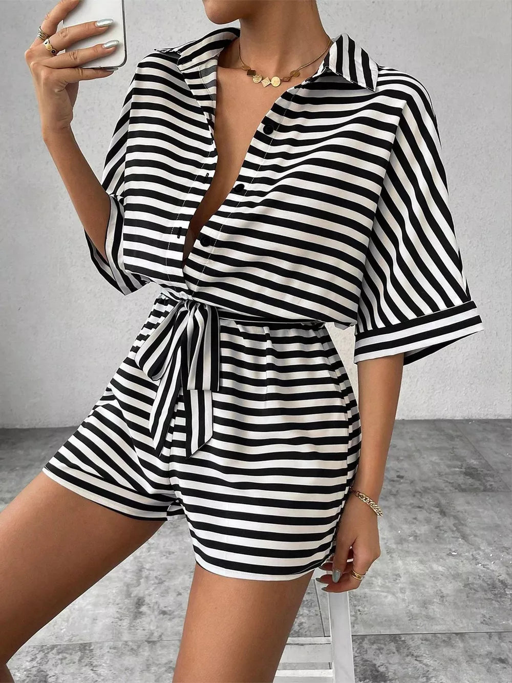 Black and white striped belted romper with collared button-front top and short sleeves.