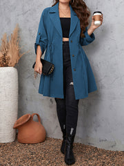Dusty blue trench coat with gathered waistline and roll-tab sleeves.
