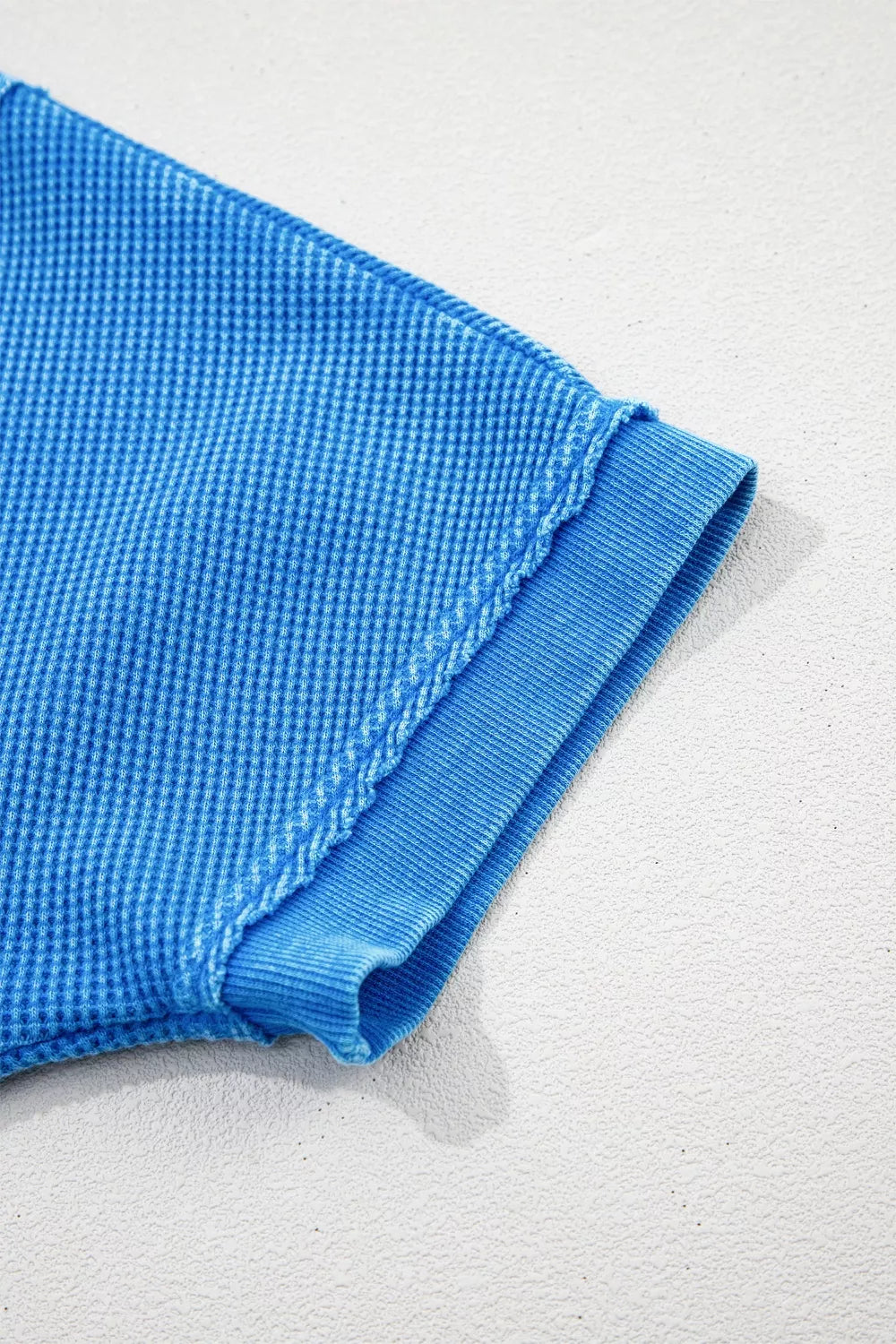 Blue mineral wash cotton t-shirt with waffle texture and ribbed cuff detail.