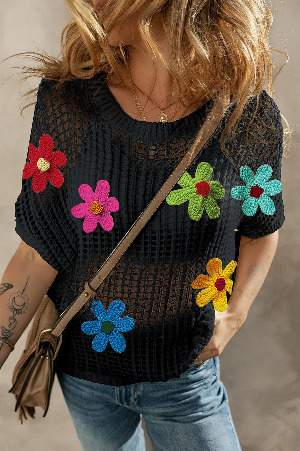 Black crochet mesh overlay top with colorful floral appliques and short sleeves.