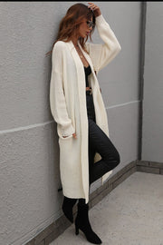 Cream textured knit maxi cardigan with pockets and open front, styled with black pants and boots.