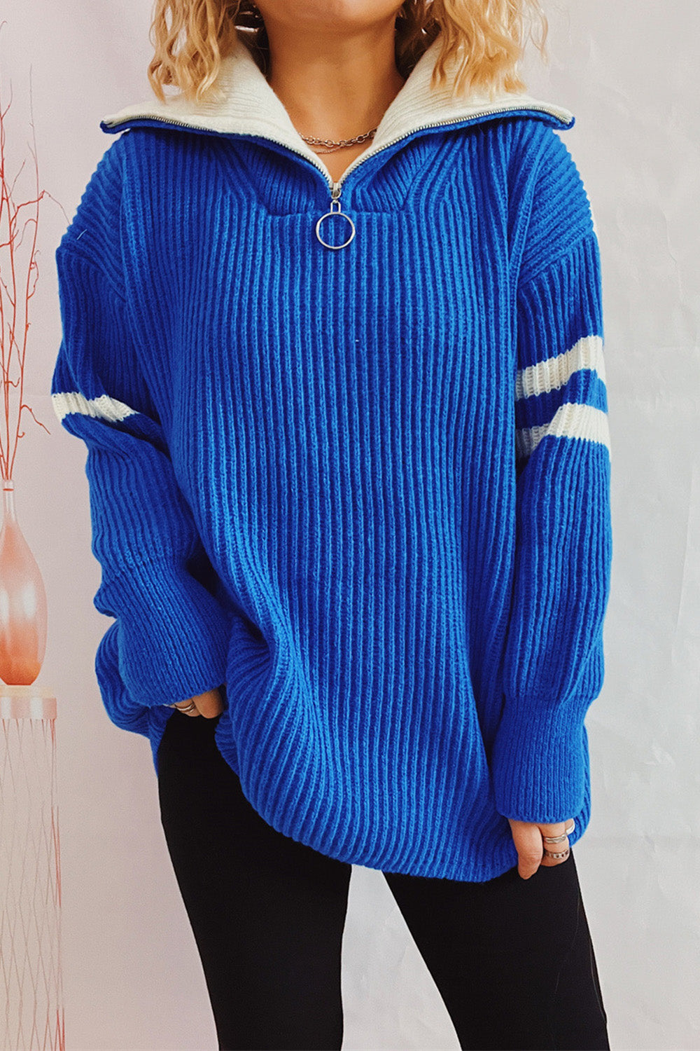Ribbed knit quarter-zip sweater in royal blue with white stripes on sleeves and cream collar.