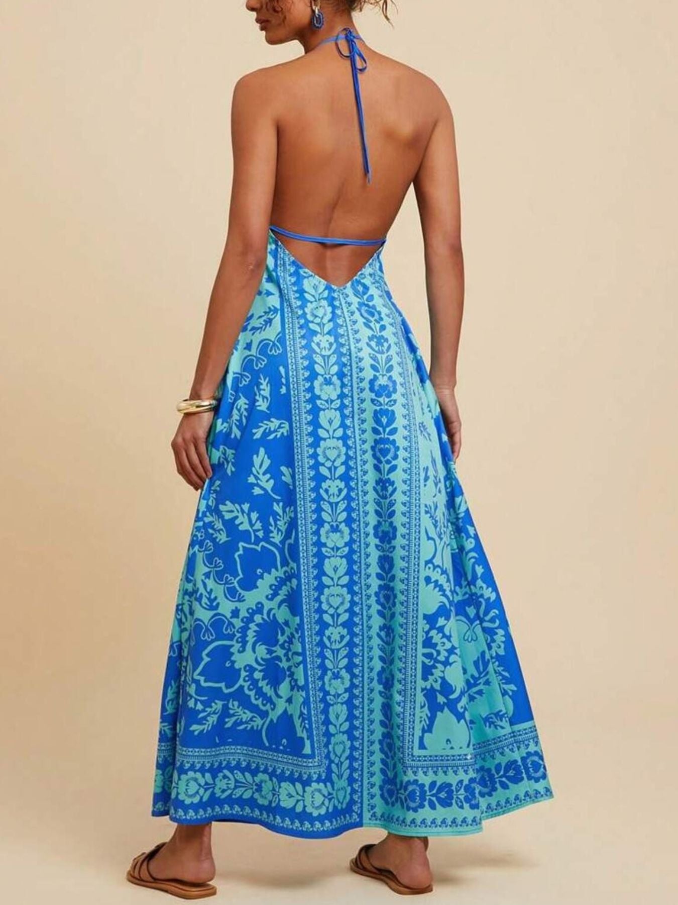 Blue floral halter maxi dress with open back and flowing skirt.