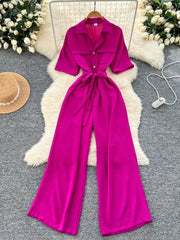 Belted wide-leg jumpsuit in pink with pockets, buttons, and short sleeves.