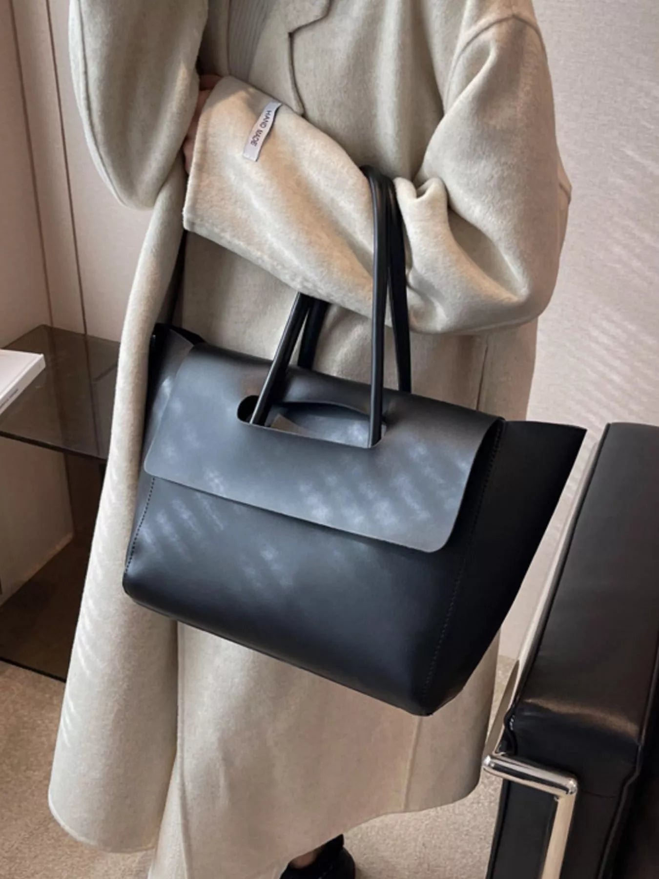 Black PU leather tote shopper bag with a fold-over flap and cut-out handle detail.