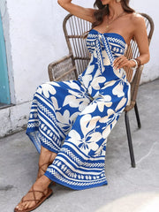 Strapless wide-leg romper in royal blue with white floral print and tie-front detail.