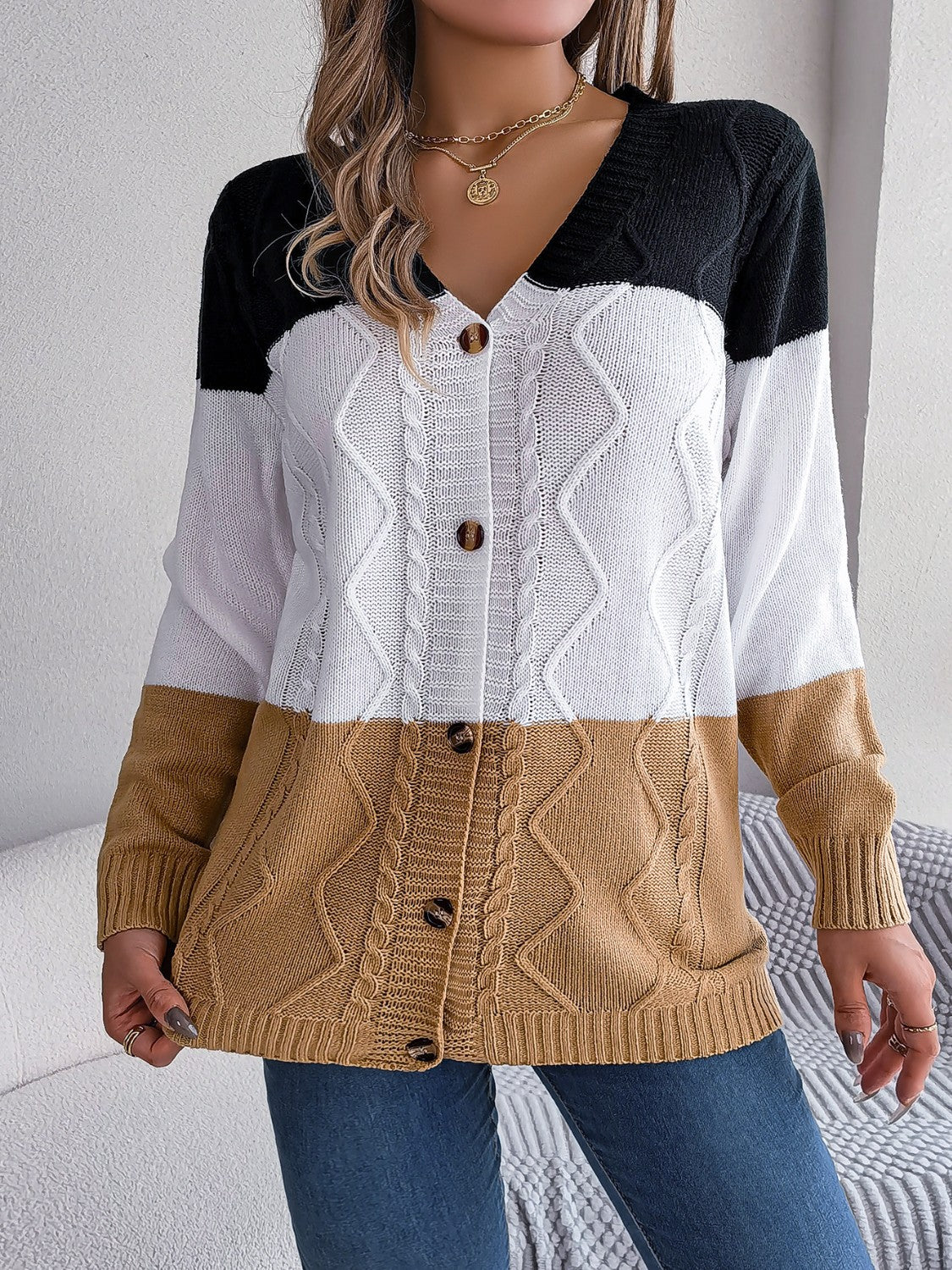 Colorblock cable knit cardigan with button front in camel, white, and black acrylic.