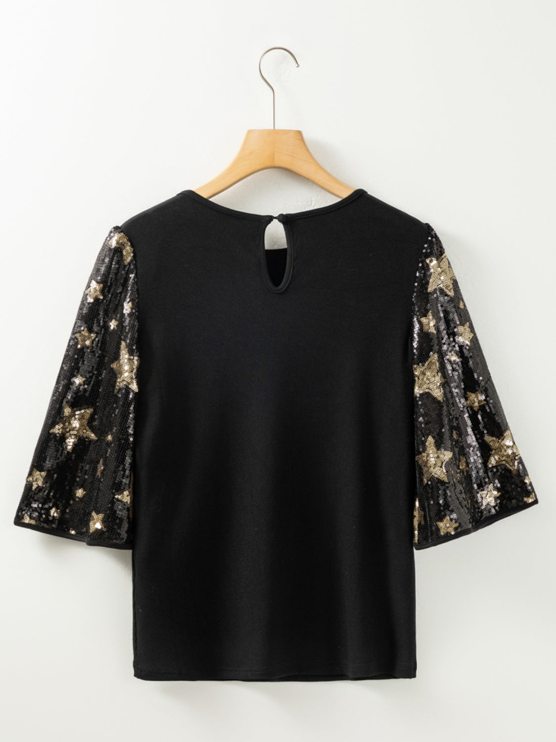 Black knit top with star sequin bell sleeves and keyhole back.