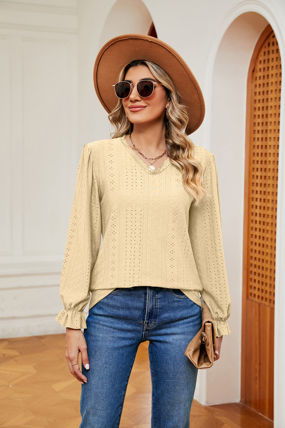 Pastel yellow perforated blouse with v-neck and ruffle cuffs.