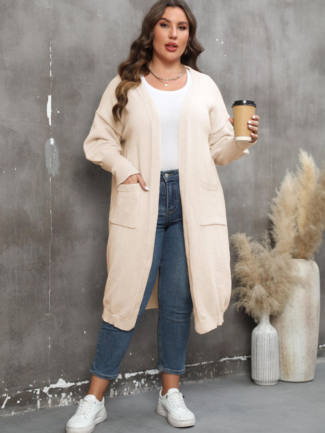Cream oversized knit duster cardigan with patch pockets and ribbed trim.