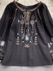 Black tie neck blouse with colorful floral embroidery and billowy sleeves.