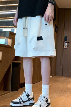 Relaxed fit ivory chino shorts with drawstring and pockets, styled with white socks and sneakers.