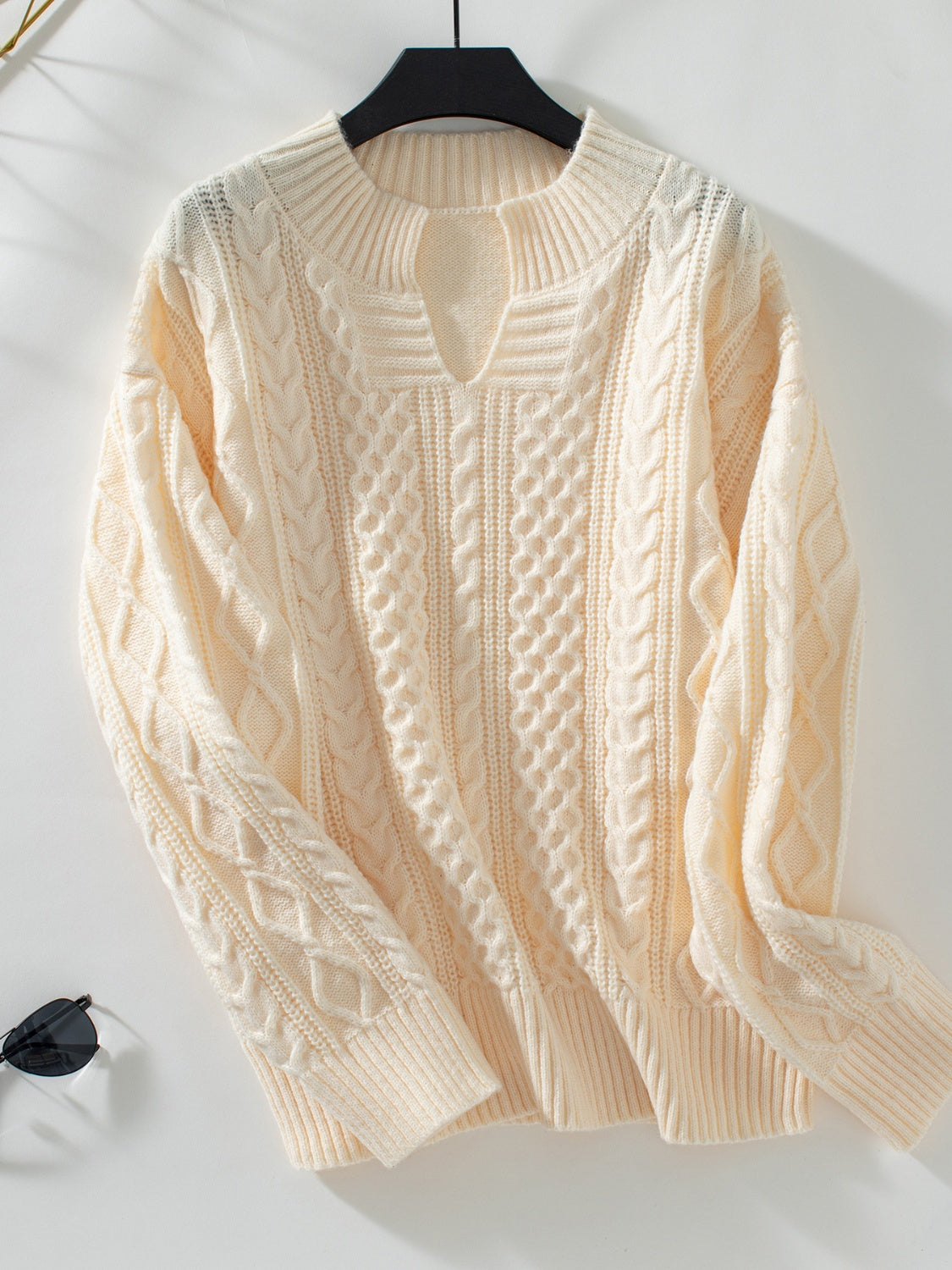 Cream cable knit sweater with keyhole neckline and ribbed cuffs.