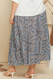 Midi skirt in blue with geometric print and pleats, styled with white sandals.