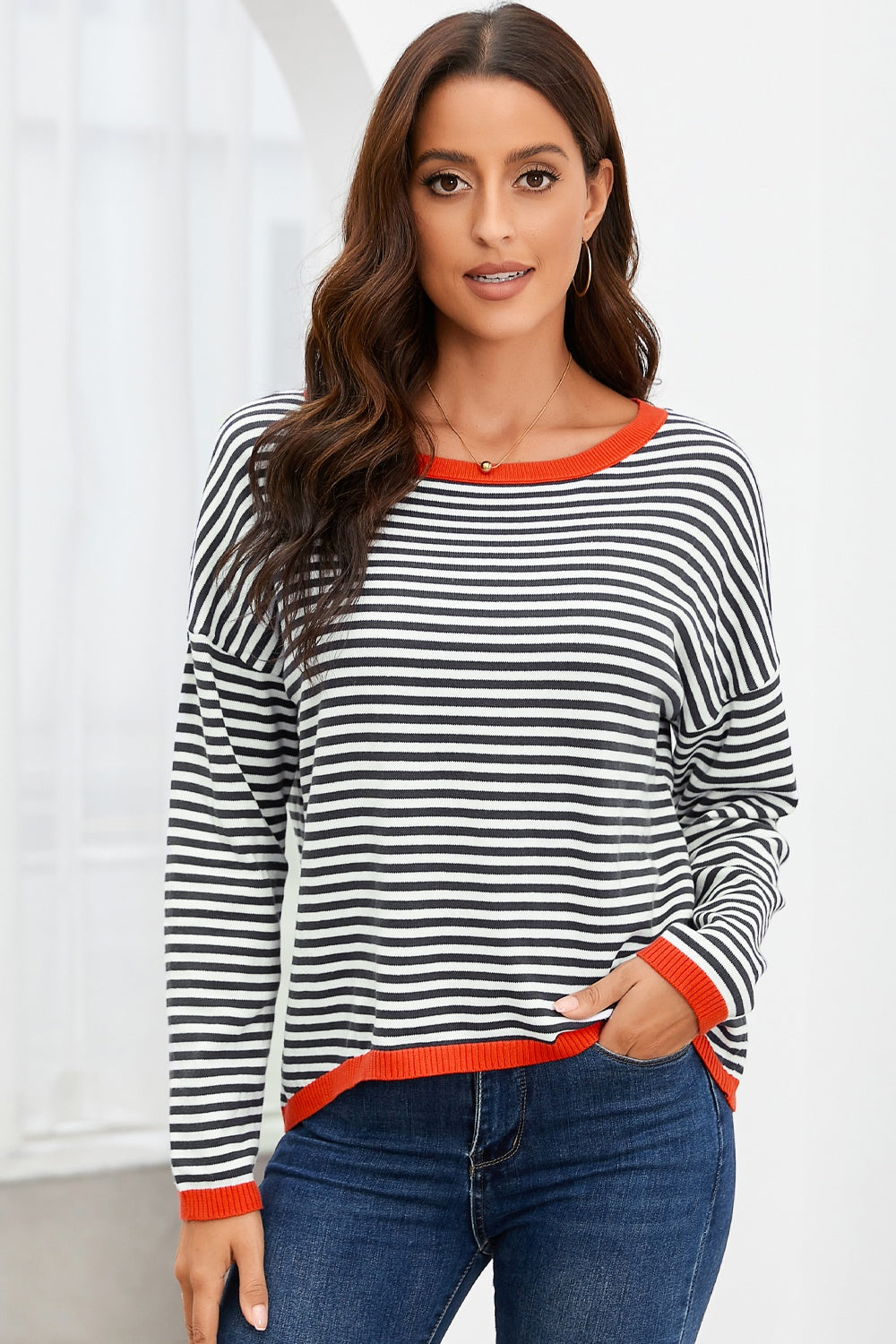 Striped knit crewneck sweater with contrast red trim and long sleeves.