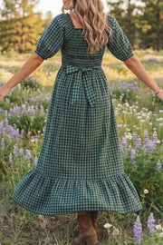 Plaid maxi dress with ruffled hem, square neckline, puff sleeves, and a tie waist.