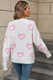 White acrylic knit pullover with a pink heart intarsia pattern and crew neck.