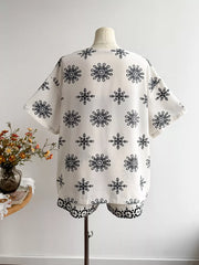 White polyester shorts set with black snowflake print top and geometric print shorts.